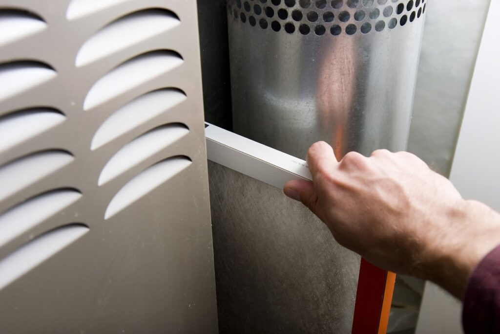 Technician replacing a furnace air filter, highlighting heating and air conditioning repair services. 